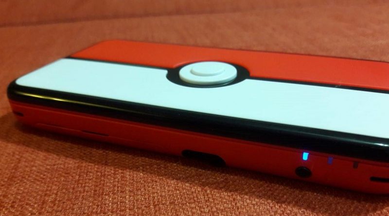 The top of a Red 2DS XL handheld against an orange background.